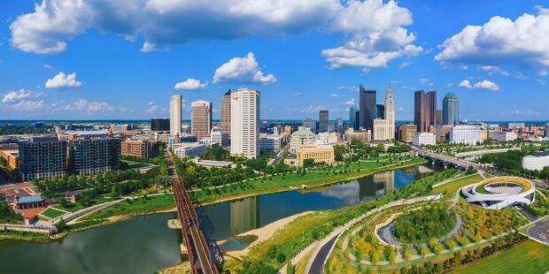 A panoramic view of Columbus skyline with river and green parks in Ohio