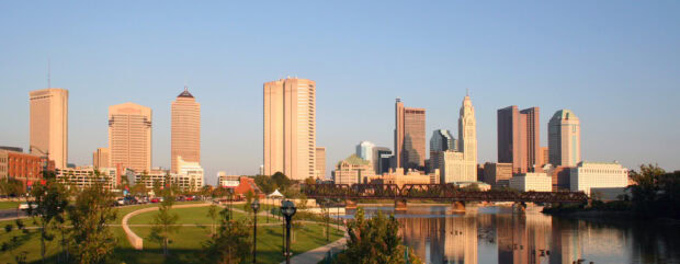 Columbus Ohio city skyline reflecting on the river at sunset with green park in foreground