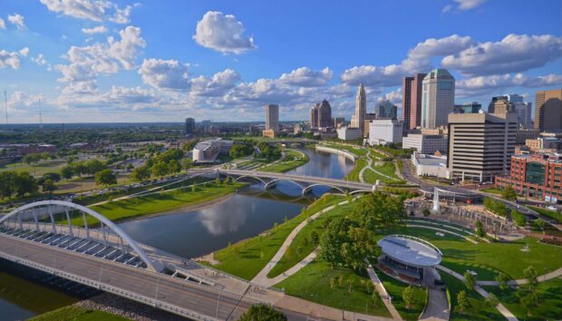 A scenic view of Columbus Ohio skyline with river and green parks on a sunny day