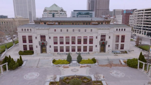 Historic Columbus building with red windows and city skyline in the background