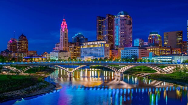Night cityscape of Columbus Ohio with illuminated buildings and river reflection