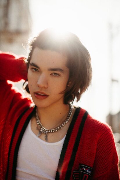 A young man wearing a red cardigan and chain necklace in soft sunlight, HD Mobile Wallpaper