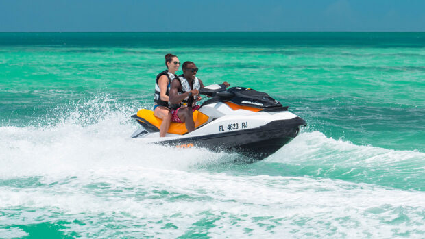 A man and woman are riding a jet ski on clear turquoise water with waves splashing, HD Desktop Wallpaper