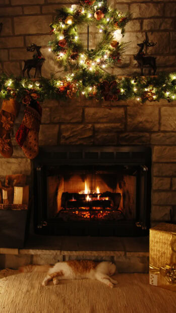 A festive fireplace decorated with lights, stockings, and a sleeping cat below, HD Mobile Wallpaper