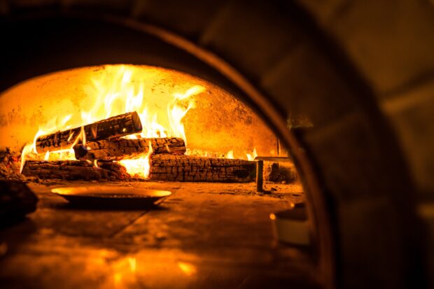 A cozy fire burns brightly in the rustic fireplace with glowing logs, 2K Desktop Wallpaper
