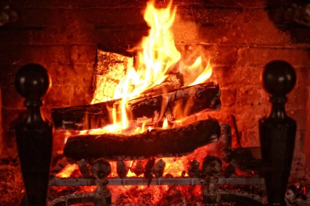 A close up of a cozy burning fire with glowing logs in a brick fireplace, 2K Desktop Wallpaper
