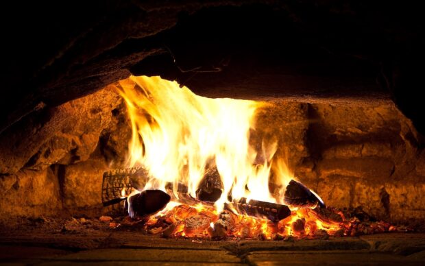 A warm fire burning on wooden logs inside a stone fireplace with glowing embers, HD Desktop Wallpaper