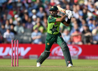 A cricket player in green uniform playing a shot on the field during a match