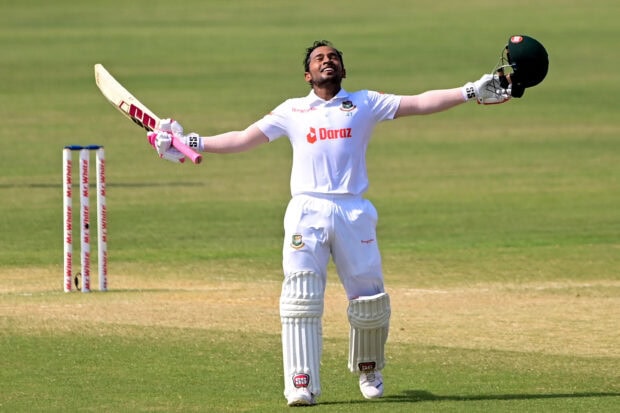 A cricket player celebrating a milestone on the cricket field with arms wide open