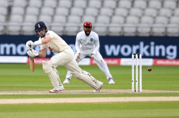A cricket player in protective gear preparing to hit the ball during a match