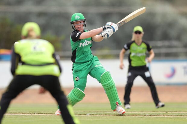 Female cricket player hitting the ball during a professional match on the cricket field