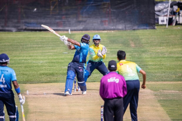 A cricket batsman hitting the ball during a professional cricket match on a sunny day