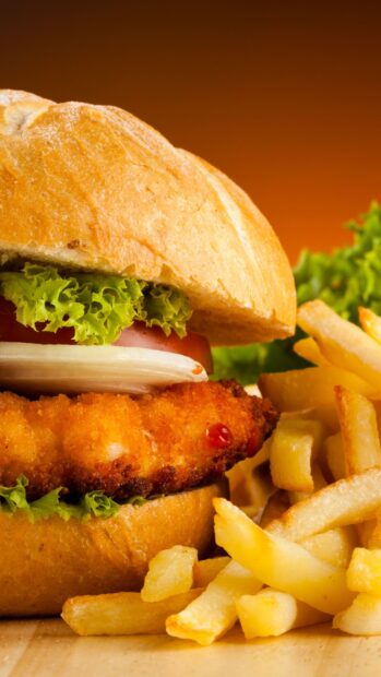 A close up of a crispy fried chicken sandwich served with fresh French fries and lettuce, 2K Phone Wallpaper