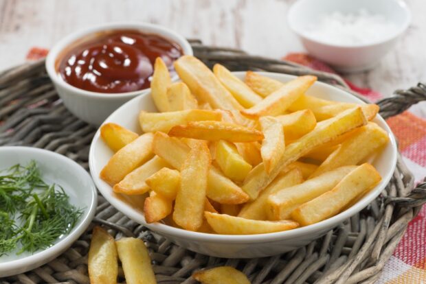 A bowl of crispy golden French fries is served with ketchup and fresh herbs, HD Desktop Wallpaper