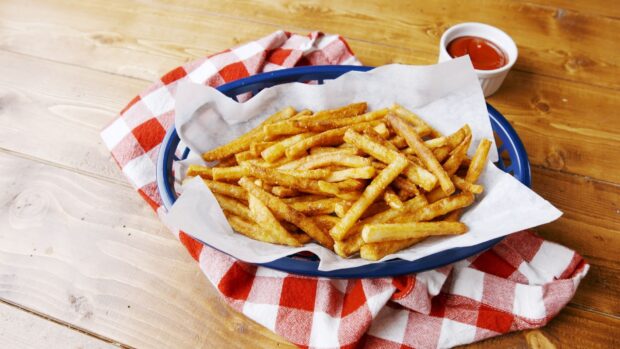 A basket of crispy golden French fries served with ketchup on a wooden table, HD Desktop Wallpaper