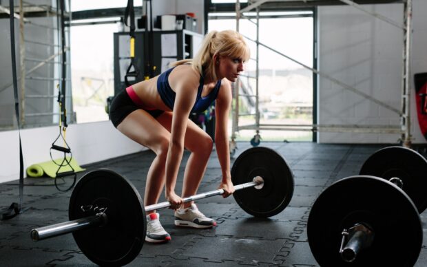A woman performing Crossfit strength training with a barbell in a gym, 2K Desktop Wallpaper
