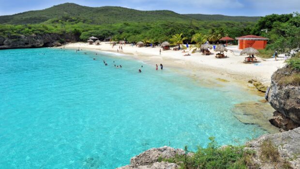 Crystal clear turquoise water and sandy beach with visitors on Curacao Island