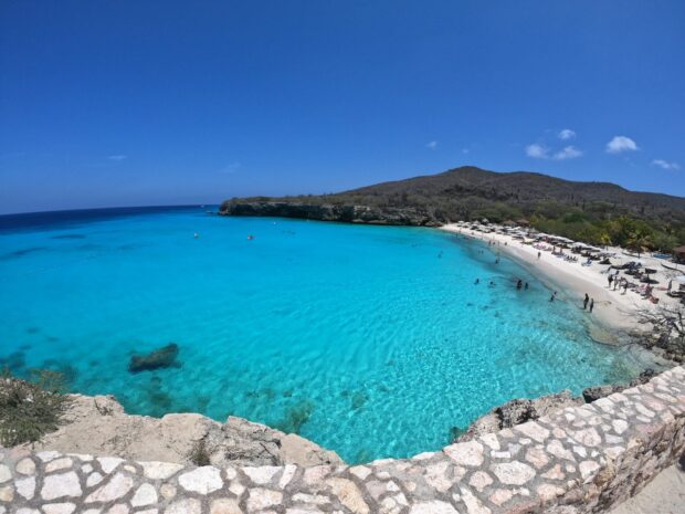 Clear turquoise water and rocky coastline at Curacao Island with sandy beach and tourists