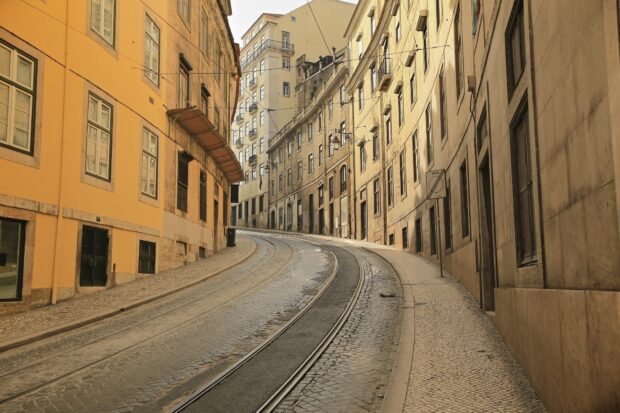 A curved tram track runs through a street lined with traditional buildings in Lisbon Portugal, HD Desktop Wallpaper