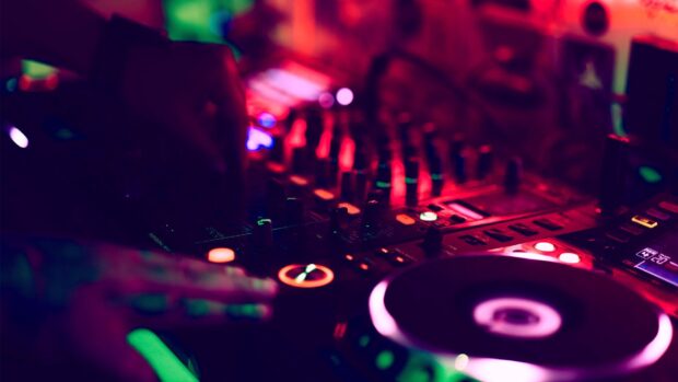 A DJ is adjusting controls on a mixing board in a nightclub setting, HD Desktop Wallpaper
