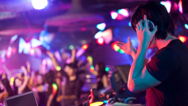 A DJ is playing music while people dance and enjoy the nightclub atmosphere, 4K Desktop Wallpaper