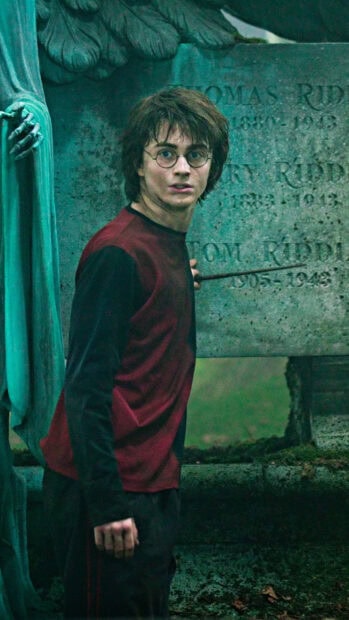 Daniel Radcliffe is casting a spell near a tombstone in a dark setting, HD Phone Wallpaper