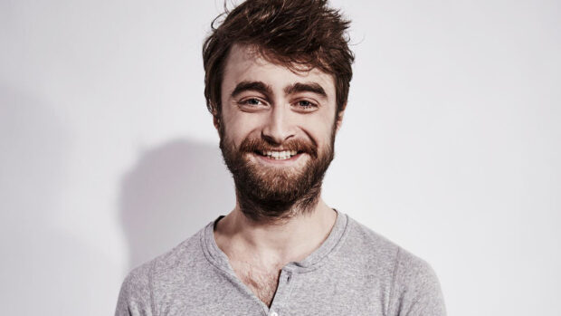 Daniel Radcliffe smiles warmly wearing a gray shirt against a plain background, HD Desktop Wallpaper