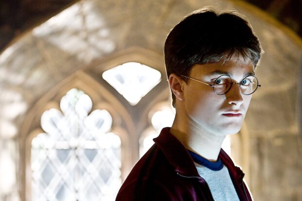 Daniel Radcliffe looks serious with round glasses in a dimly lit gothic setting, HD Desktop Wallpaper