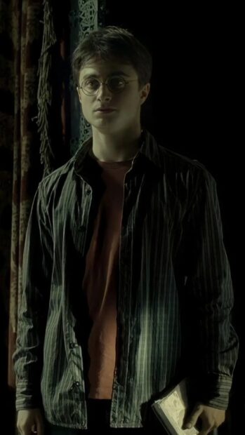 Daniel Radcliffe stands holding a book with a thoughtful expression, HD Mobile Wallpaper