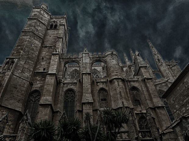 Một công trình kiến ​​trúc Gothic lịch sử đứng dưới bầu trời tối và nhiều mây, trưng bày các chi tiết đá phức tạp, Hình nền máy tính HD