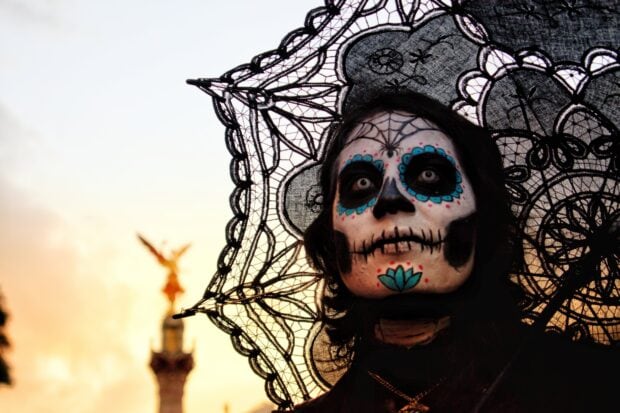 A person with Day of the Dead face paint wearing a lace veil in Mexico City during sunset, HD Desktop Wallpaper