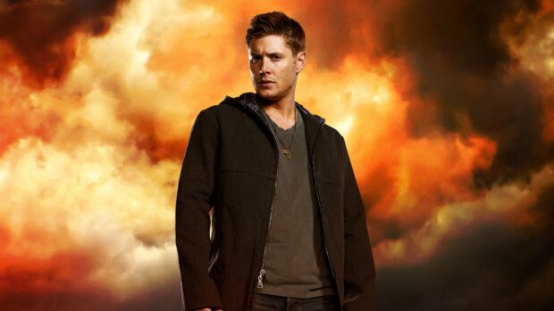 Dean Winchester standing confidently in front of a fiery sky background