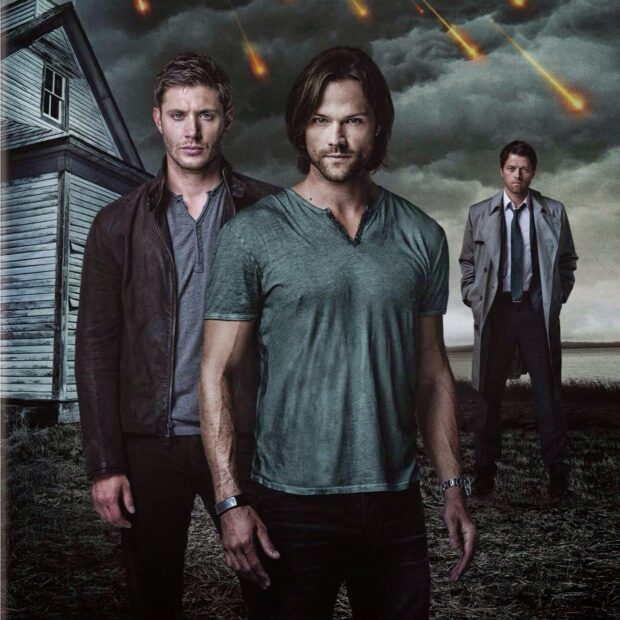 Dean Winchester with his brother standing in front of a house under a dark sky with fiery meteors falling