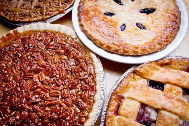 A variety of pies including pecan and fruit pies arranged on a wooden table, HD Desktop Wallpaper