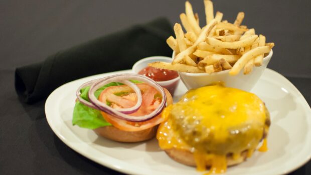 A cheeseburger topped with melted cheese served with crispy French fries and fresh vegetables, 4K Desktop Wallpaper