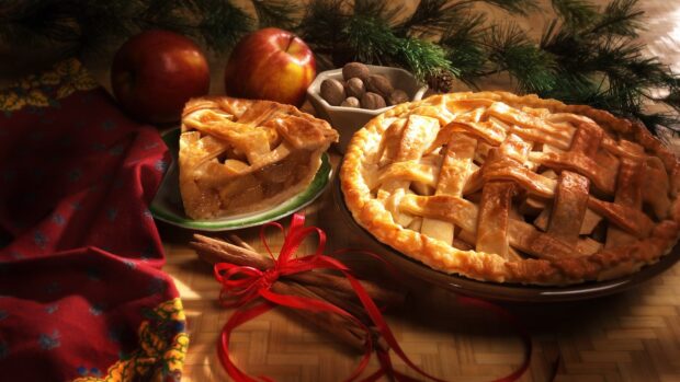 A homemade pie with apples on a wooden table beside cinnamon sticks and nuts, HD Desktop Wallpaper