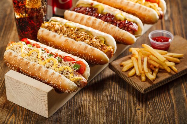 A selection of hot dogs with various toppings served alongside crispy french fries on a rustic table, HD Desktop Wallpaper