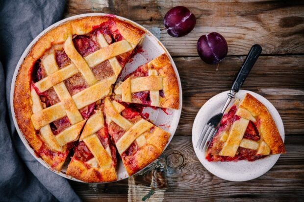 A sliced plum pie with a lattice crust on a wooden table, HD Desktop Wallpaper