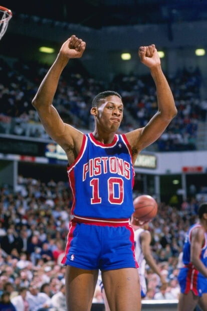 Dennis Rodman wearing a Pistons jersey celebrating on the basketball court