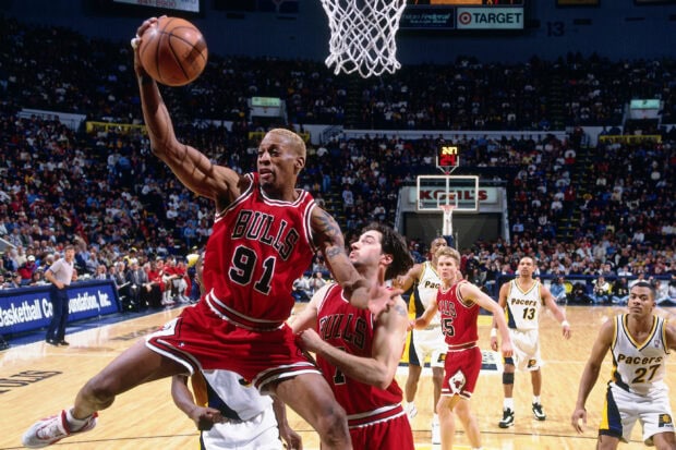 Dennis Rodman in a Chicago Bulls jersey making a basketball play during an intense game against the Pacers