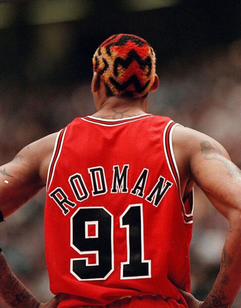 Dennis Rodman wearing a red jersey with number 91 and colorful patterned hair viewed from the back
