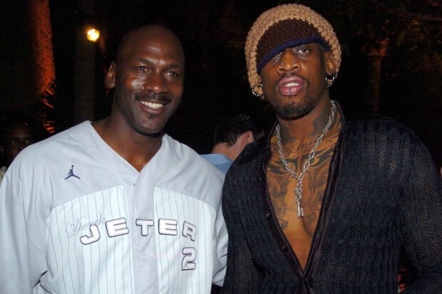 Dennis Rodman wearing a knit hat and multiple piercings with a man in a white Derek Jeter jersey
