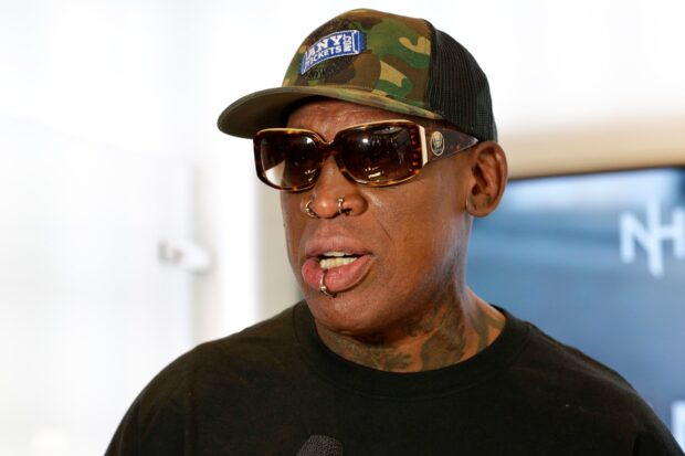 Dennis Rodman wearing sunglasses and a cap with facial piercings and tattoos