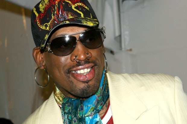 Dennis Rodman wearing a cap and sunglasses with facial piercings and a scarf around his neck
