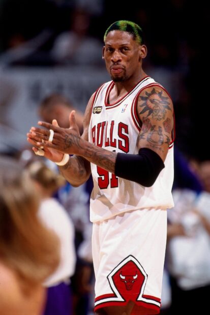 Dennis Rodman in Chicago Bulls jersey clapping during a basketball game with tattoos visible
