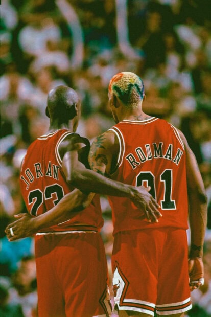 Dennis Rodman with colorful hair standing beside Michael Jordan on the basketball court