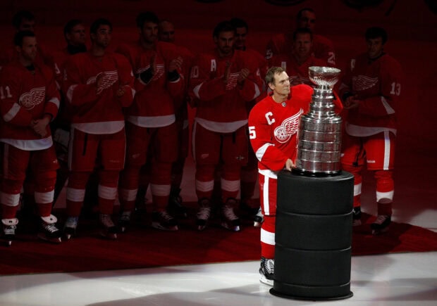 Detroit Red Wings captain holding the Stanley Cup trophy with team members applauding in the background