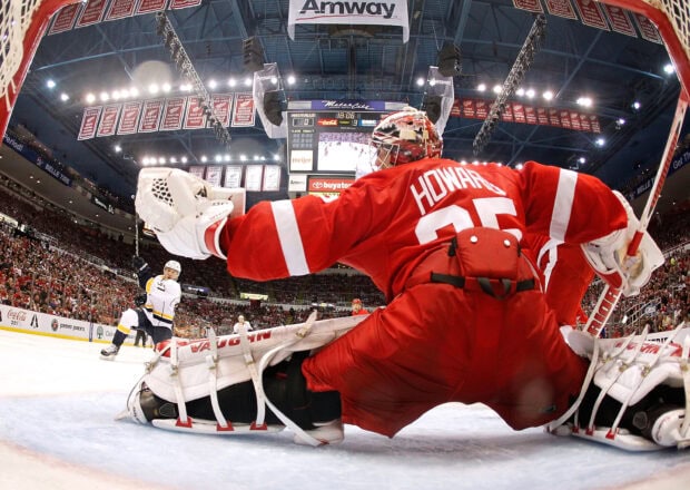 Detroit Red Wings goalie making a save during a hockey game in a crowded arena