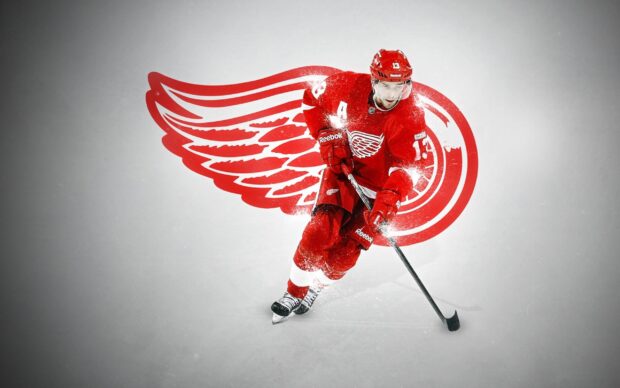 A Detroit Red Wings player skating with a hockey stick in front of the team logo