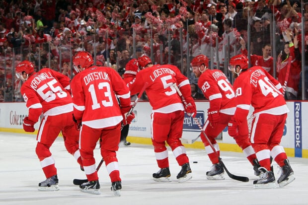 Detroit Red Wings players celebrating on ice during a hockey game with a cheering crowd in the background